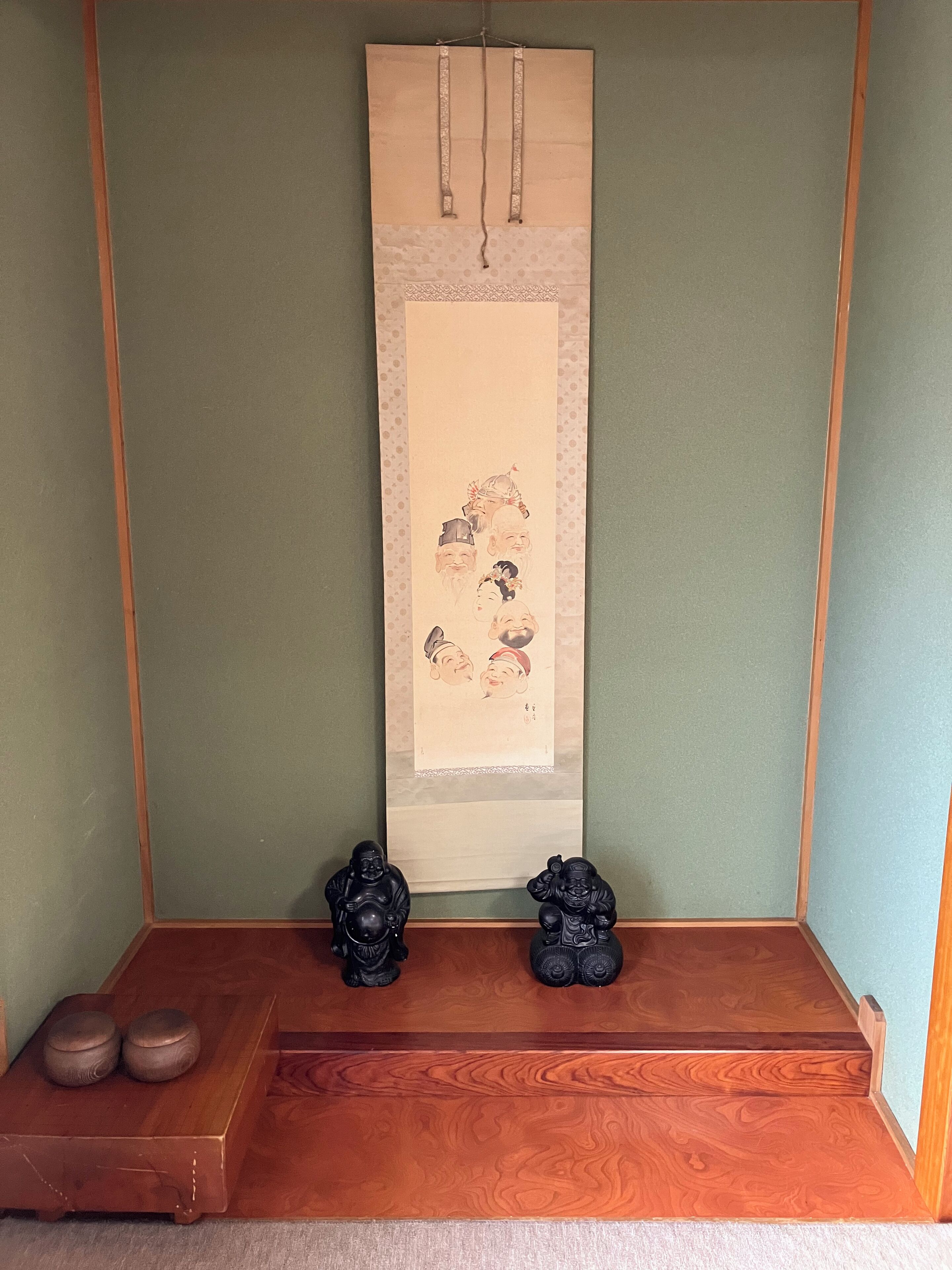 A traditional Japanese room with a tatami mat floor, a shoji screen, and two black statues on a wooden platform.