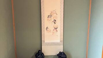 A traditional Japanese room with a tatami mat floor, a shoji screen, and two black statues on a wooden platform.