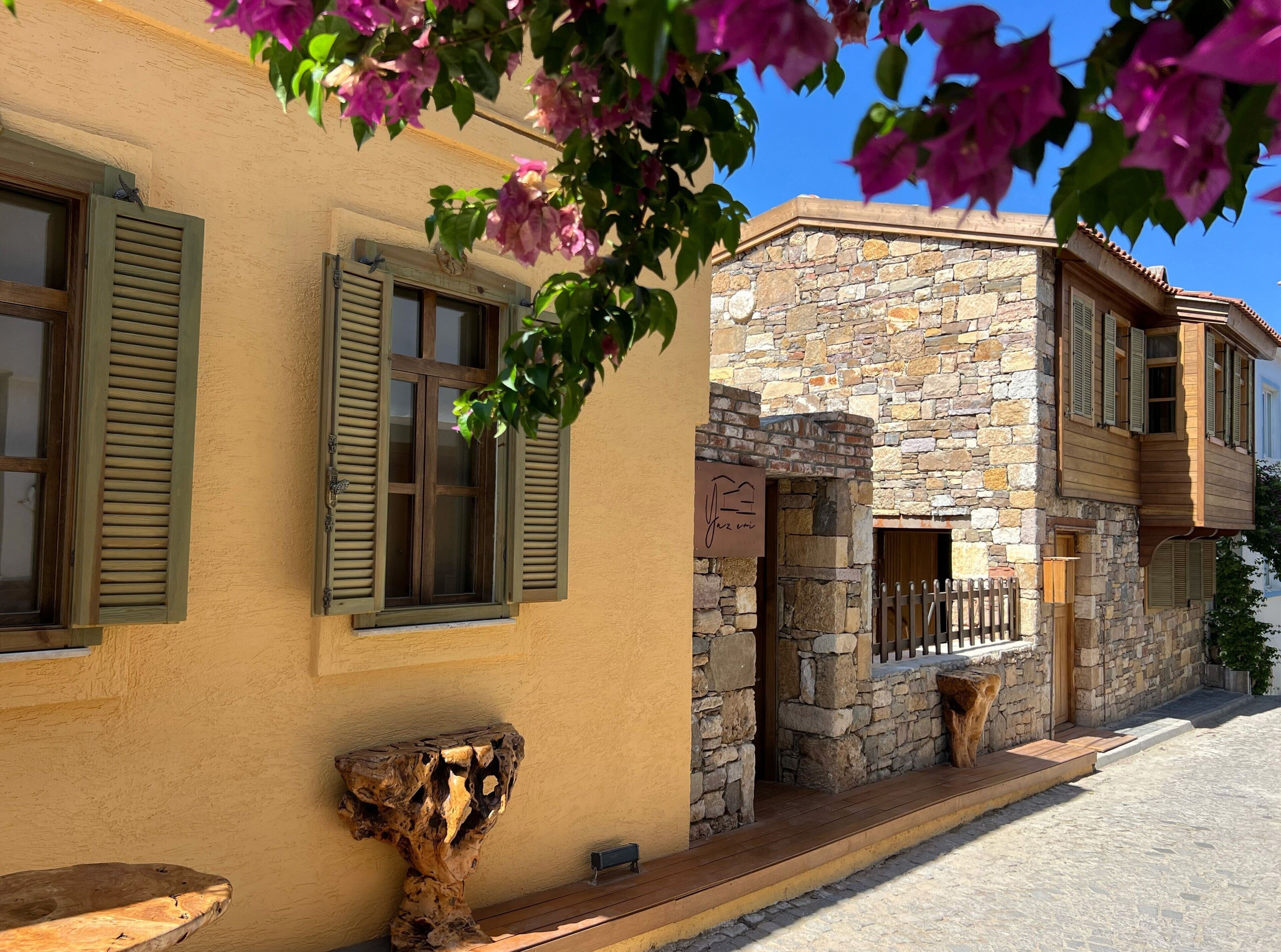 Un edificio con paredes de piedra, contraventanas de madera y un balcón.