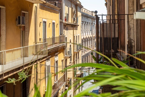 A narrow street between buildings with balconies, some with railings, and a clear sky.