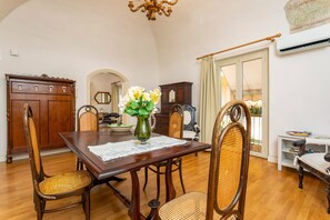 Un coin repas avec une table en bois, des chaises en osier, un vase de fleurs et un lustre.