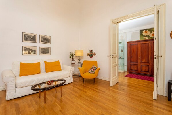 A living room with a white sofa, a round coffee table, a yellow armchair, and a wooden cabinet.