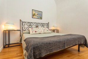 Ein Bett mit Metallgestell, zwei Nachttische, ein Wandbild und ein Holzboden.
