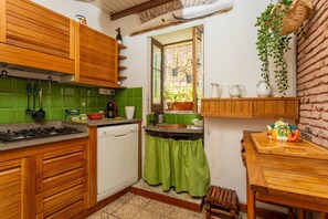 Une cuisine avec des meubles en bois, une cuisinière, un évier et une fenêtre donnant sur un paysage verdoyant.