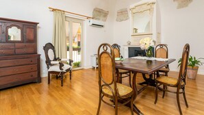A dining area with a wooden table, six wicker chairs, a wooden cabinet, and a mirror on the wall. - Apartment 'Tancredi' with Mountain View, Wi-Fi and Air Conditioning (Catania)