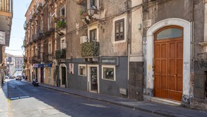 A street with a building featuring a shop named 'moretti compact' and a large wooden door. - Apartment 'Tancredi' with Mountain View, Wi-Fi and Air Conditioning (Catania)