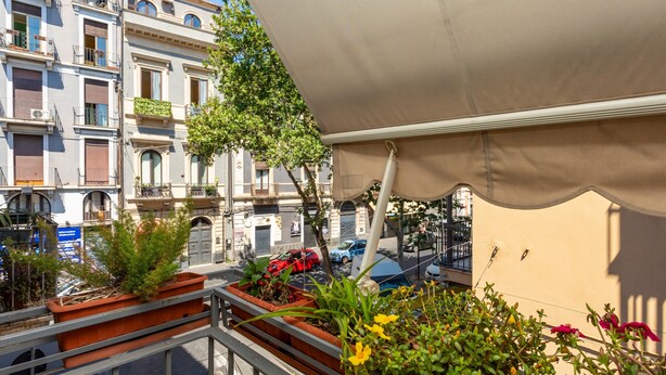 A balcony with potted plants and a view of a street with buildings. - Apartment 'Tancredi' with Mountain View, Wi-Fi and Air Conditioning (Catania)