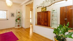 A room with wooden flooring, a large mirror, a wooden cabinet, and a potted plant. - Apartment 'Tancredi' with Mountain View, Wi-Fi and Air Conditioning (Catania)
