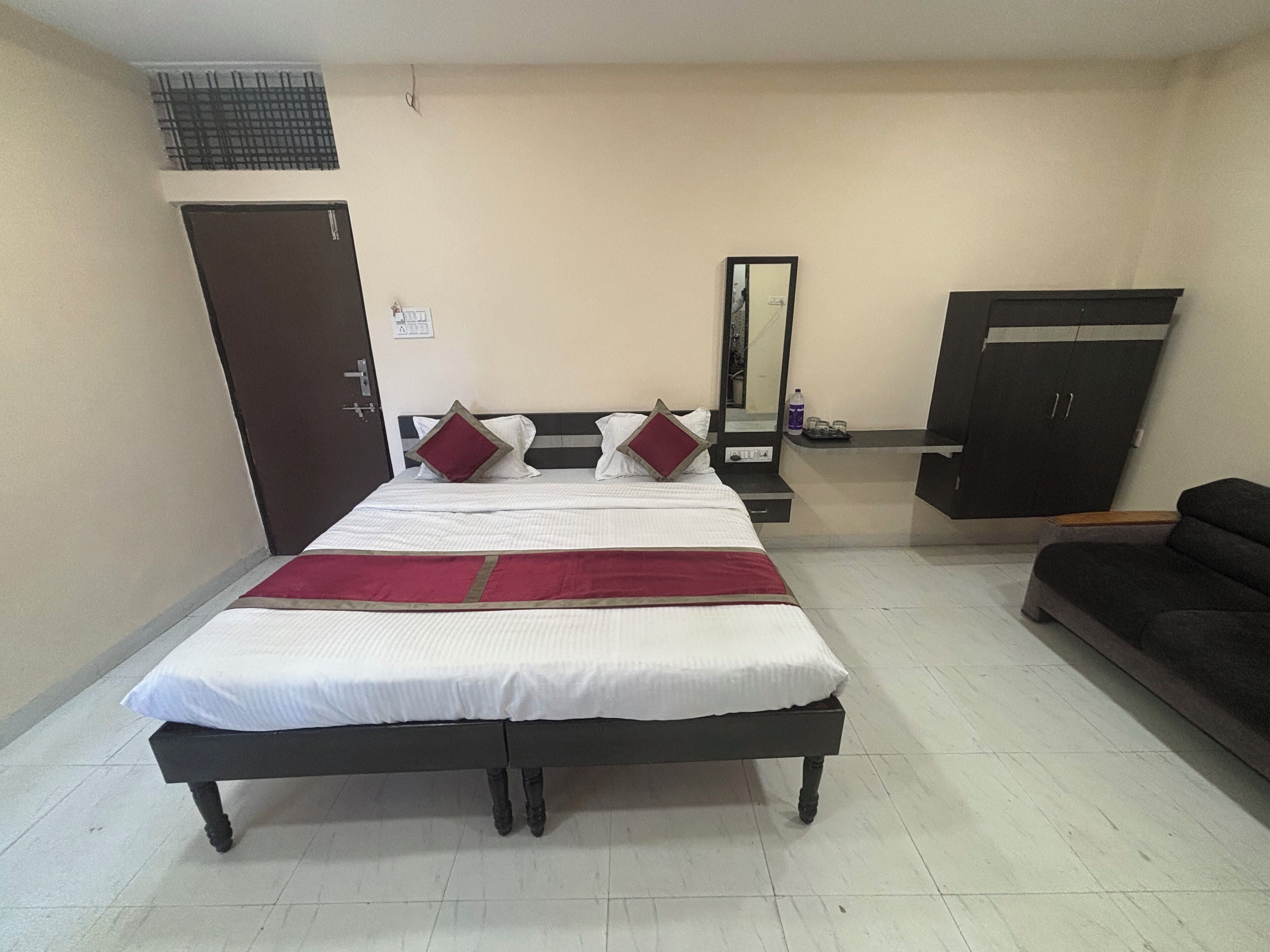 A bedroom with a bed, a wardrobe, a mirror, and a sofa.