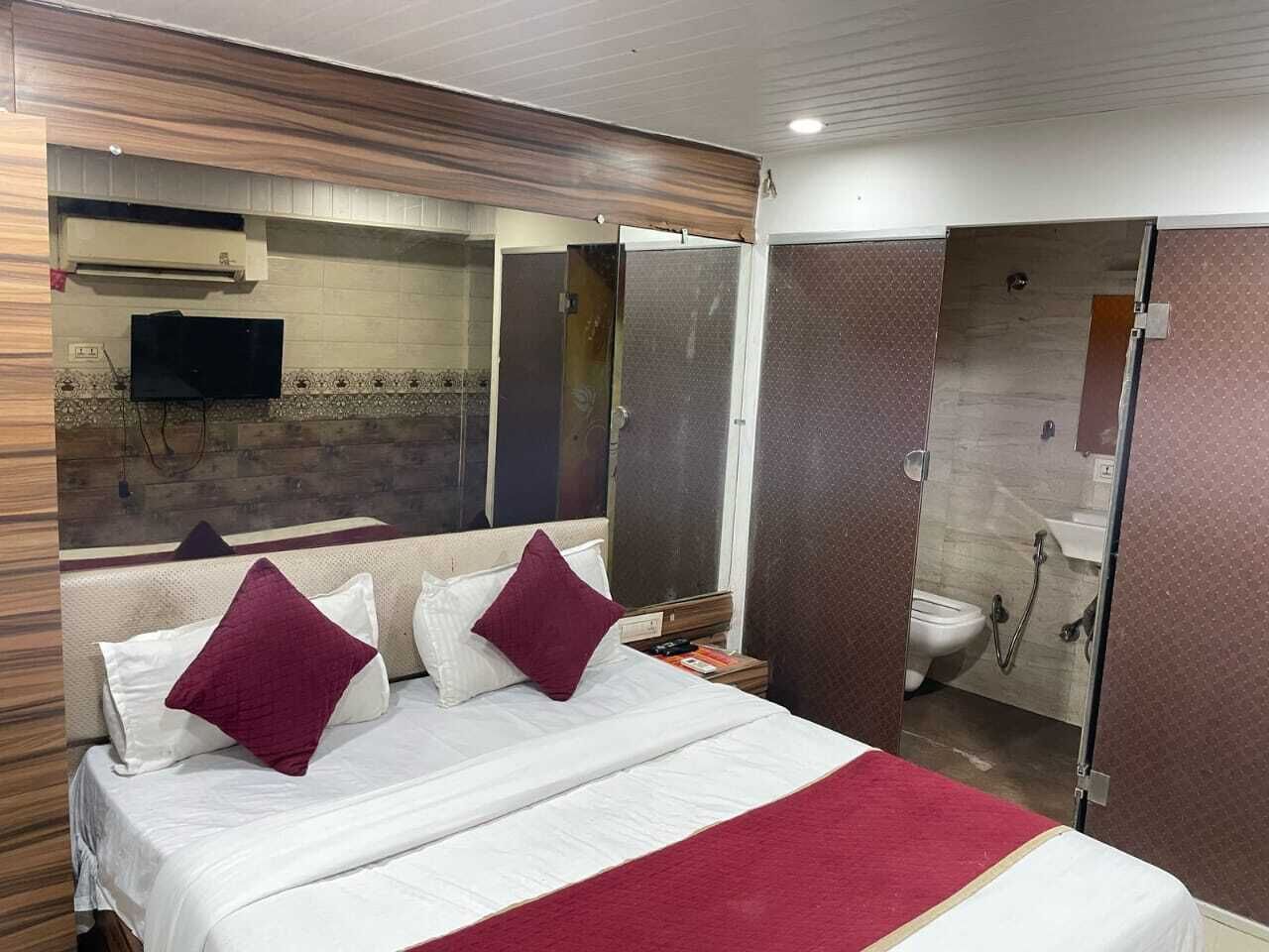 A hotel room with a bed, a TV, a shower, and a toilet.