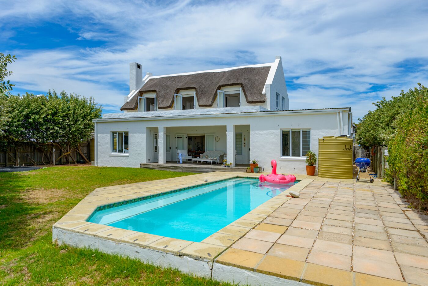 A two-story house with a swimming pool, a patio, and a fenced backyard.