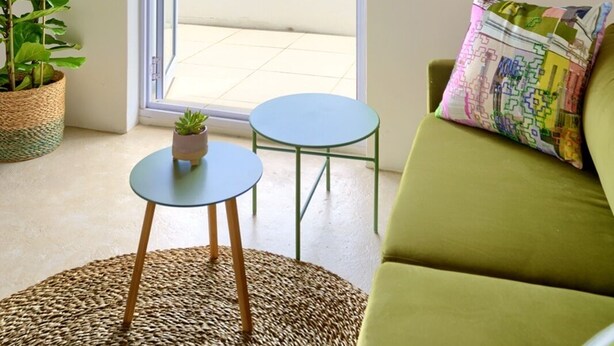 Une pièce chaleureuse avec un canapé vert, une petite table et une plante en pot.