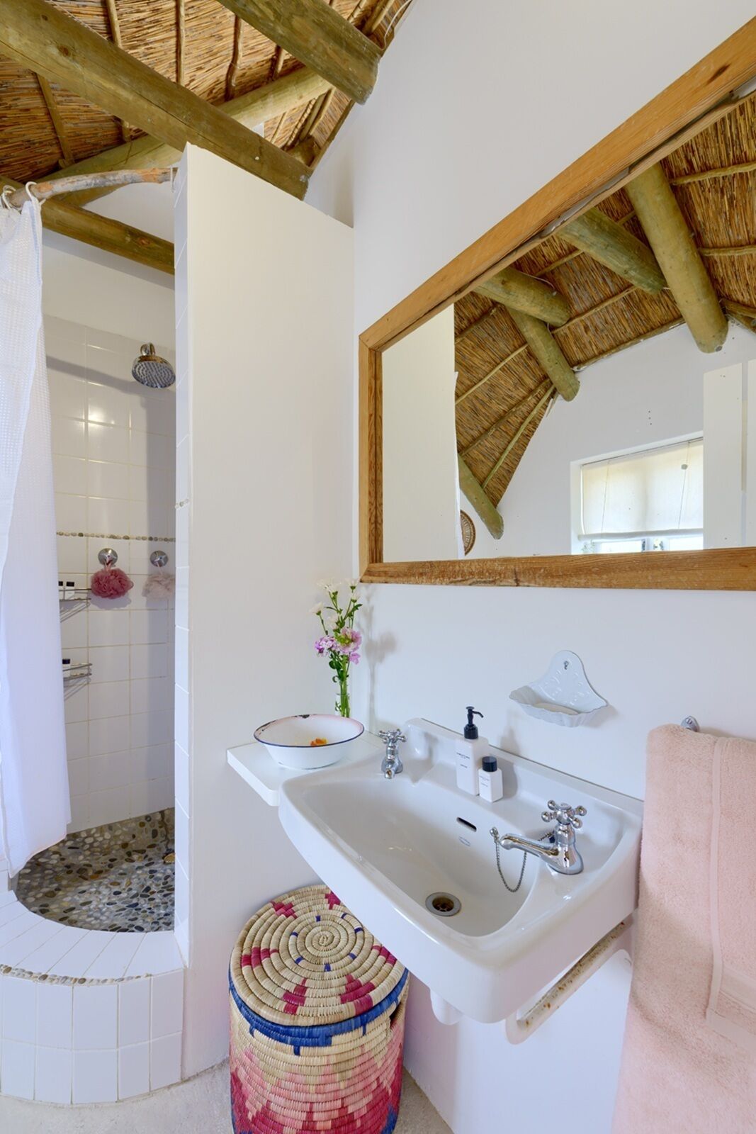 A bathroom with a shower, a sink, a mirror, and a towel rack.