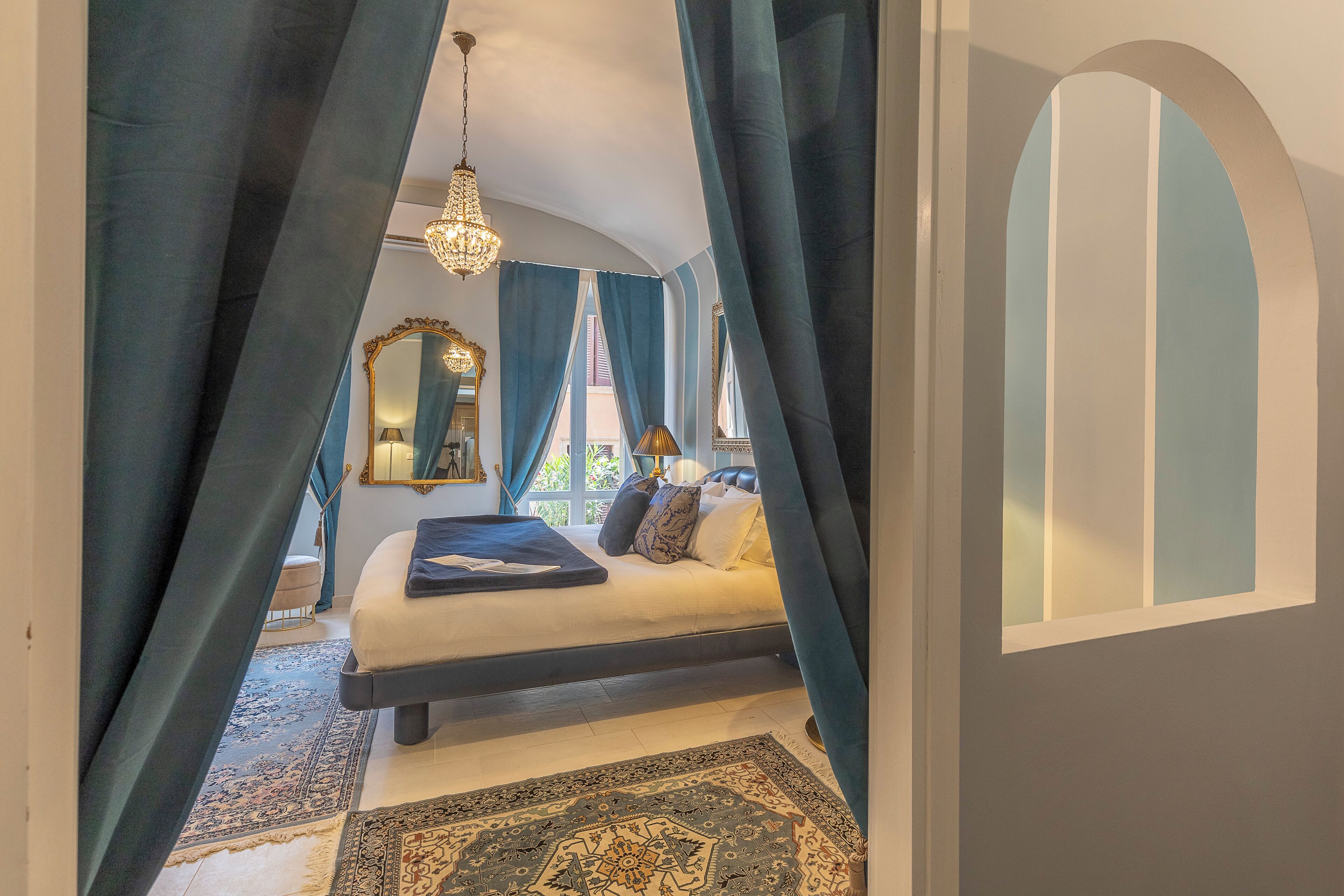 Ein Schlafzimmer mit einem Bett, einer Kandelaber, einem Spiegel und Vorhängen.
