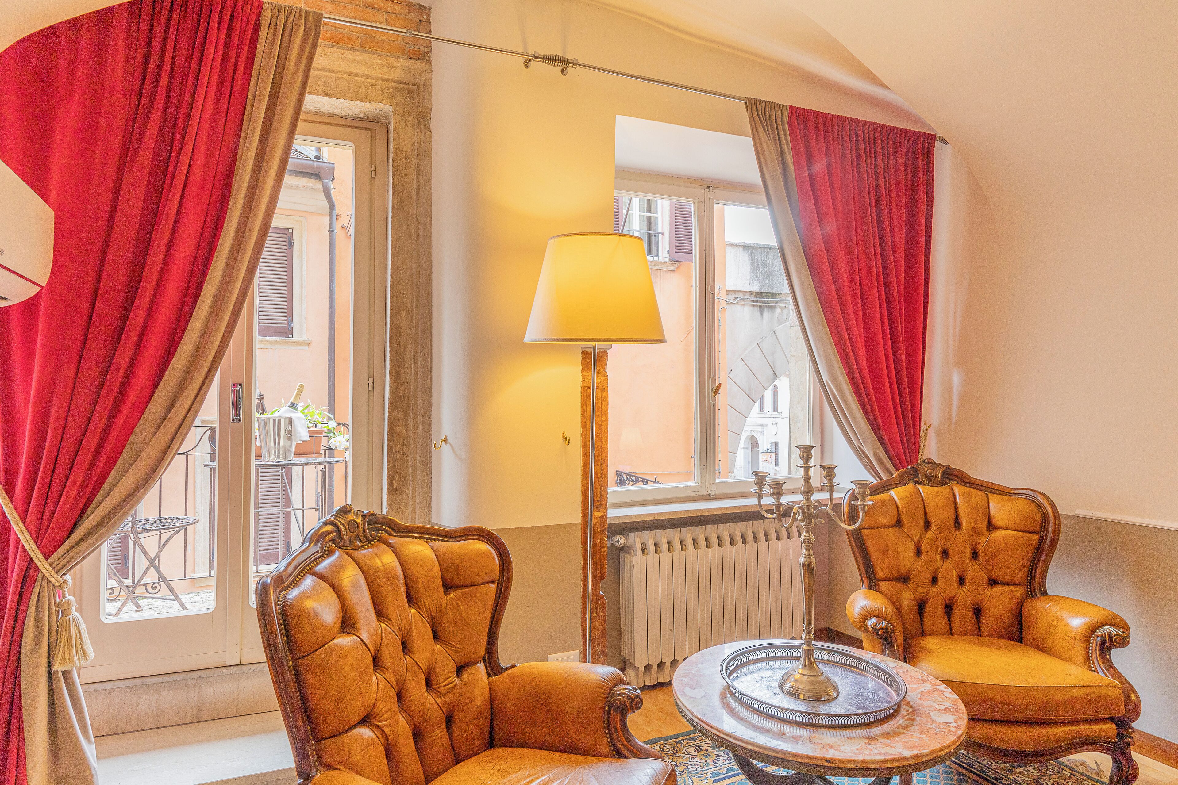 A room with two leather armchairs, a table with a decorative centerpiece, and a floor lamp.