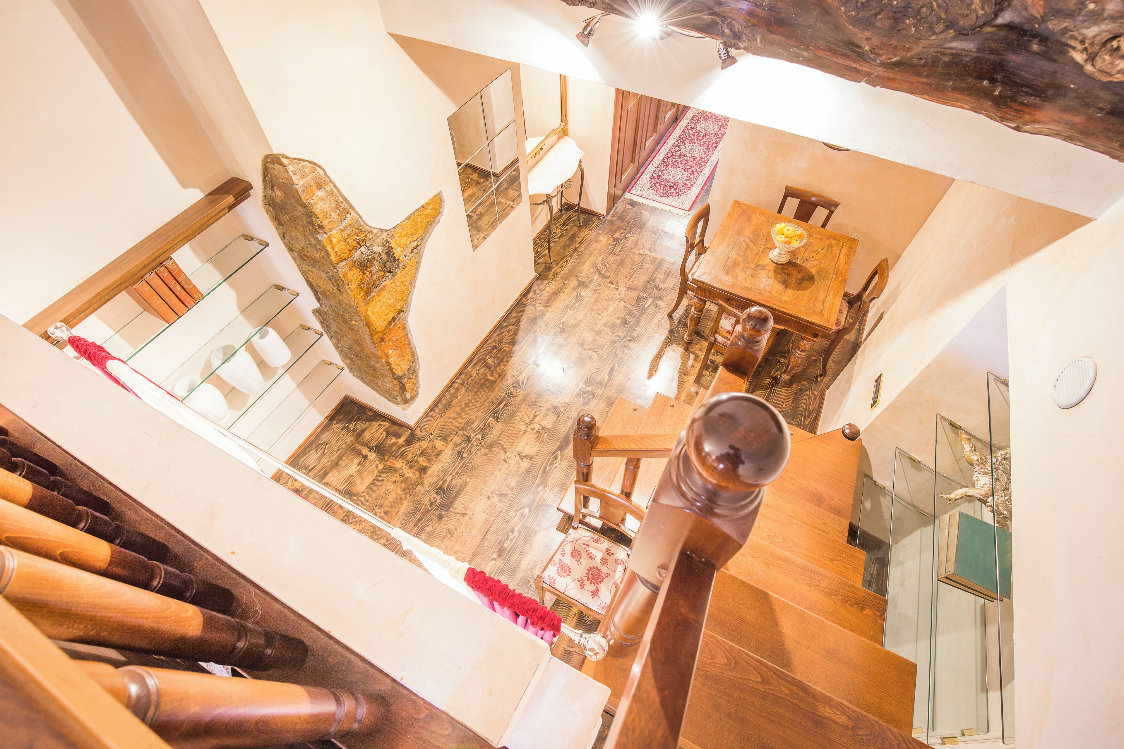 A staircase leading to a dining area with a wooden table and chairs, a stone accent wall, and a glass railing.