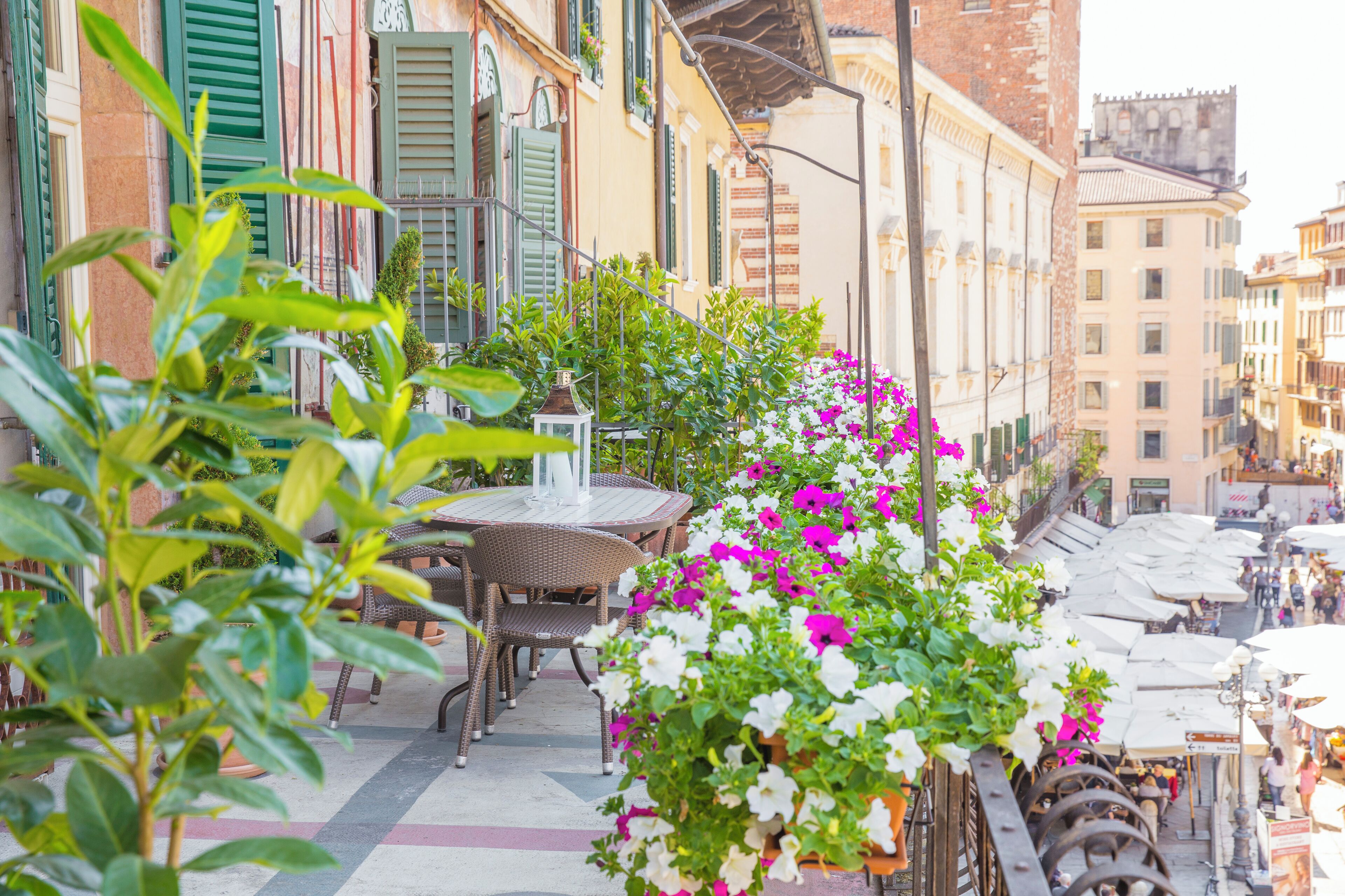 A terrace with outdoor seating, potted plants, and a view of the street.
