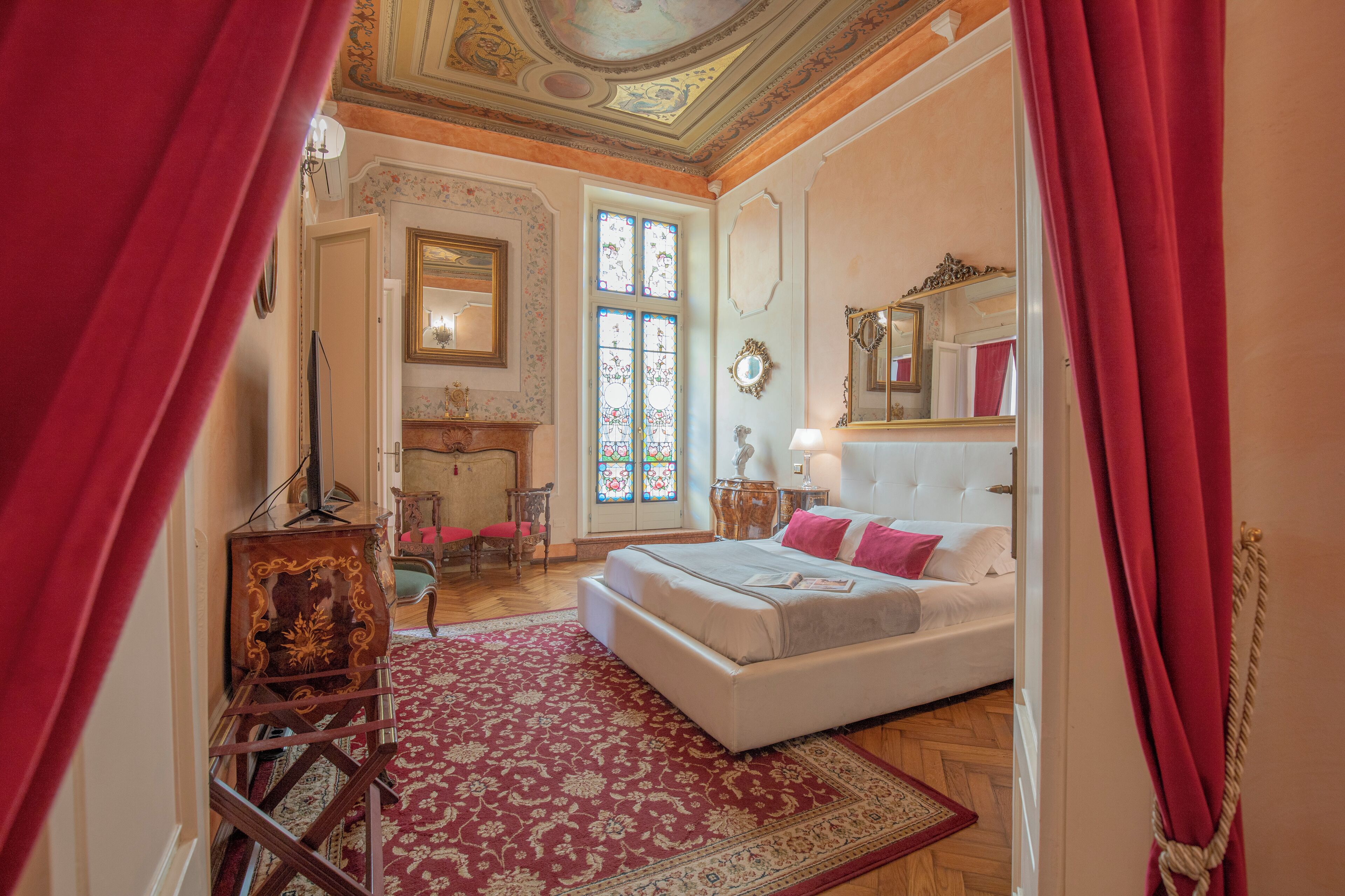 A bedroom with a large bed, a fireplace, and a stained glass window.