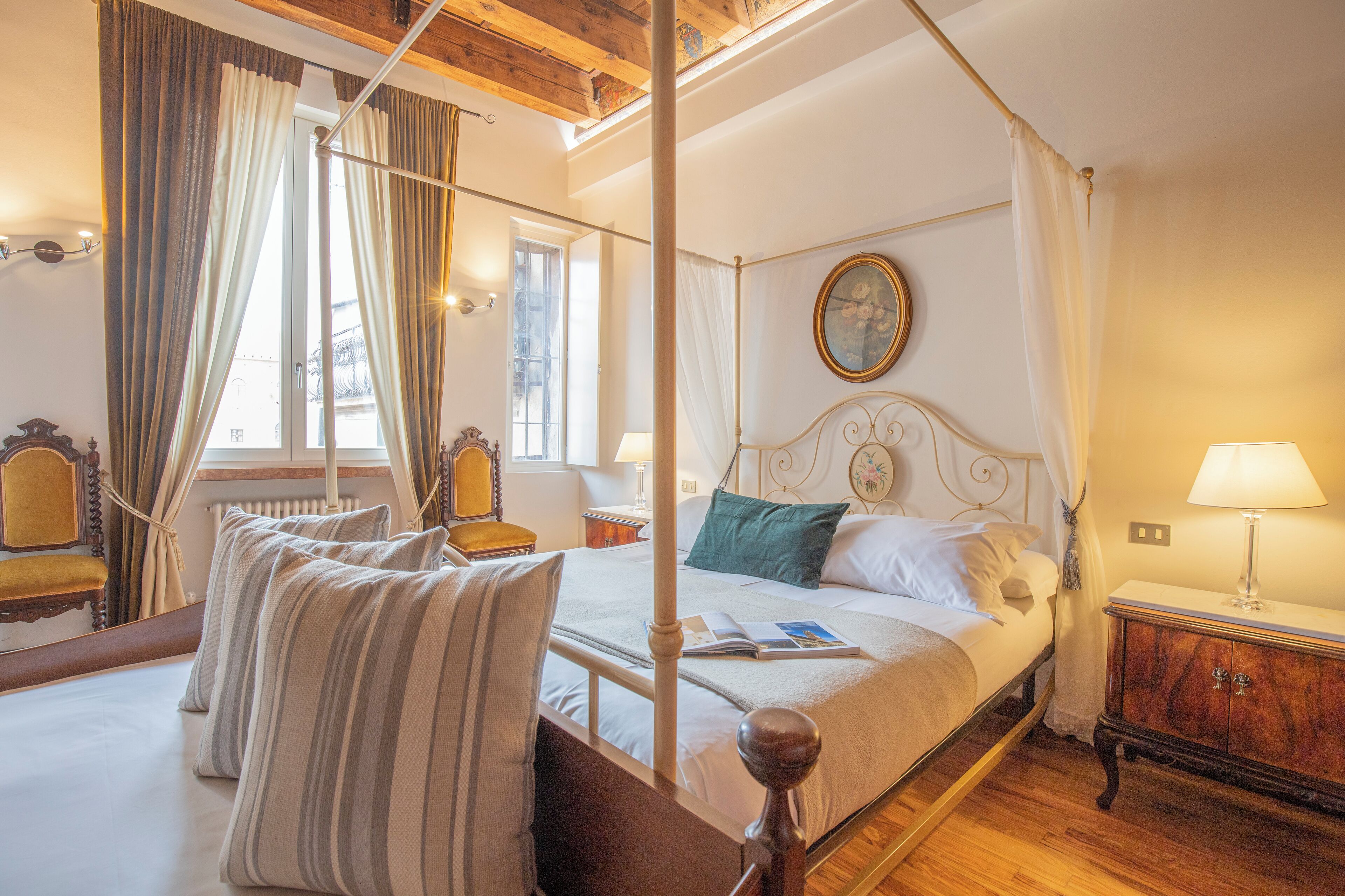 A four-poster bed with a canopy, a wooden headboard, and a bedside table with a lamp.