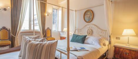 A four-poster bed with a canopy, a wooden headboard, and a bedside table with a lamp.