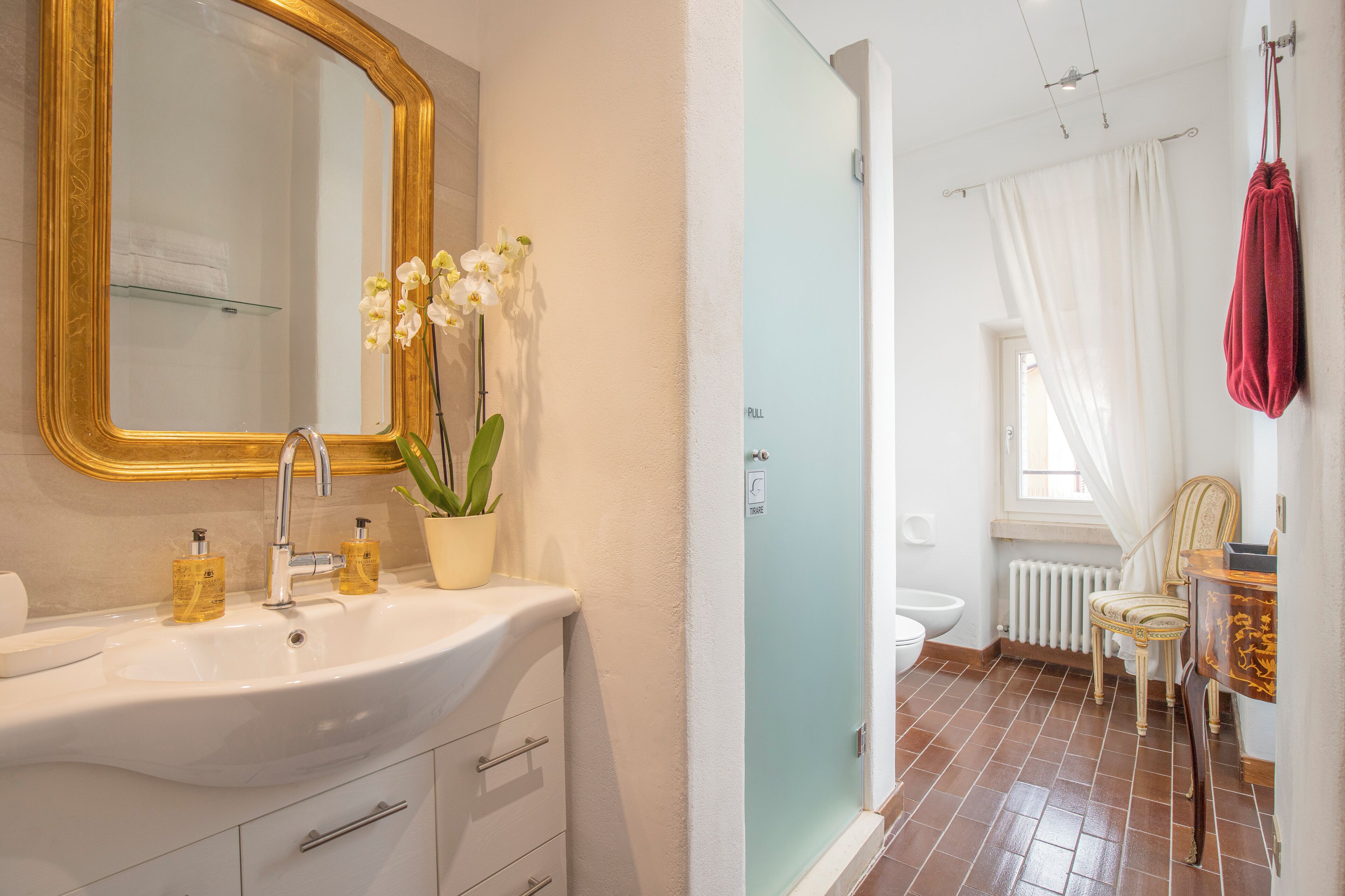 A bathroom with a sink, mirror, and a potted orchid.