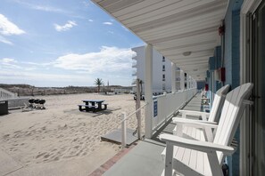 Un hôtel situé en bord de mer, doté d’un balcon couvert, d’un espace extérieur aménagé et d’une plage de sable.
