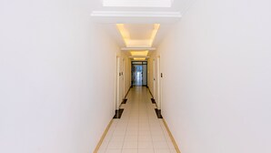 A long, narrow hallway with white walls and a tiled floor, leading to a door at the end. - Chaleunxay Hotel (Vientiane)