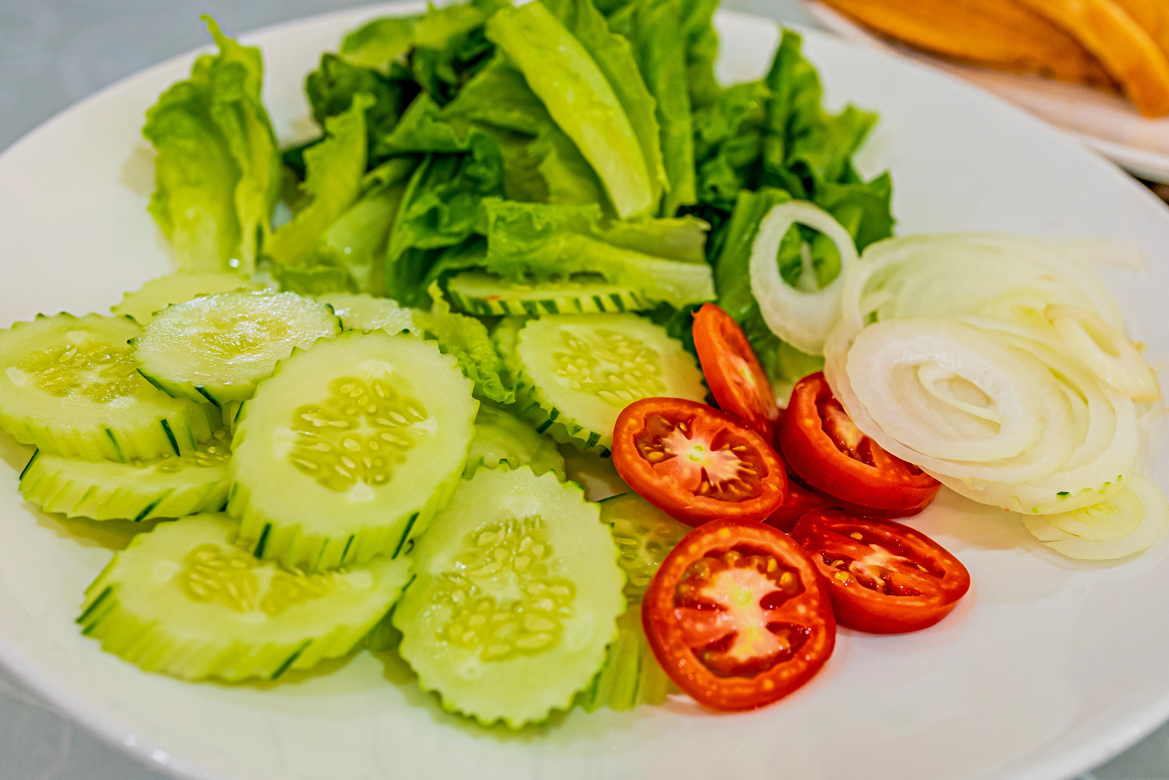 A plate of sliced cucumbers, tomatoes, and onions.