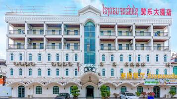 A multi-story building with a central entrance, balconies, and a sign indicating it is a hotel.