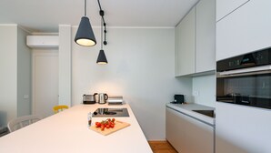 A modern kitchen with a central island, white cabinetry, a built-in oven, and pendant lighting. - MGH - Lake & Love Apartment (Gardone Riviera)