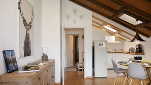 A spacious kitchen with wooden cabinets, a dining area with modern chairs, and a large deer antler artwork on the wall. - Lovely apartment for 5 guests with WIFI, pool, TV, balcony and panoramic view (Falera)