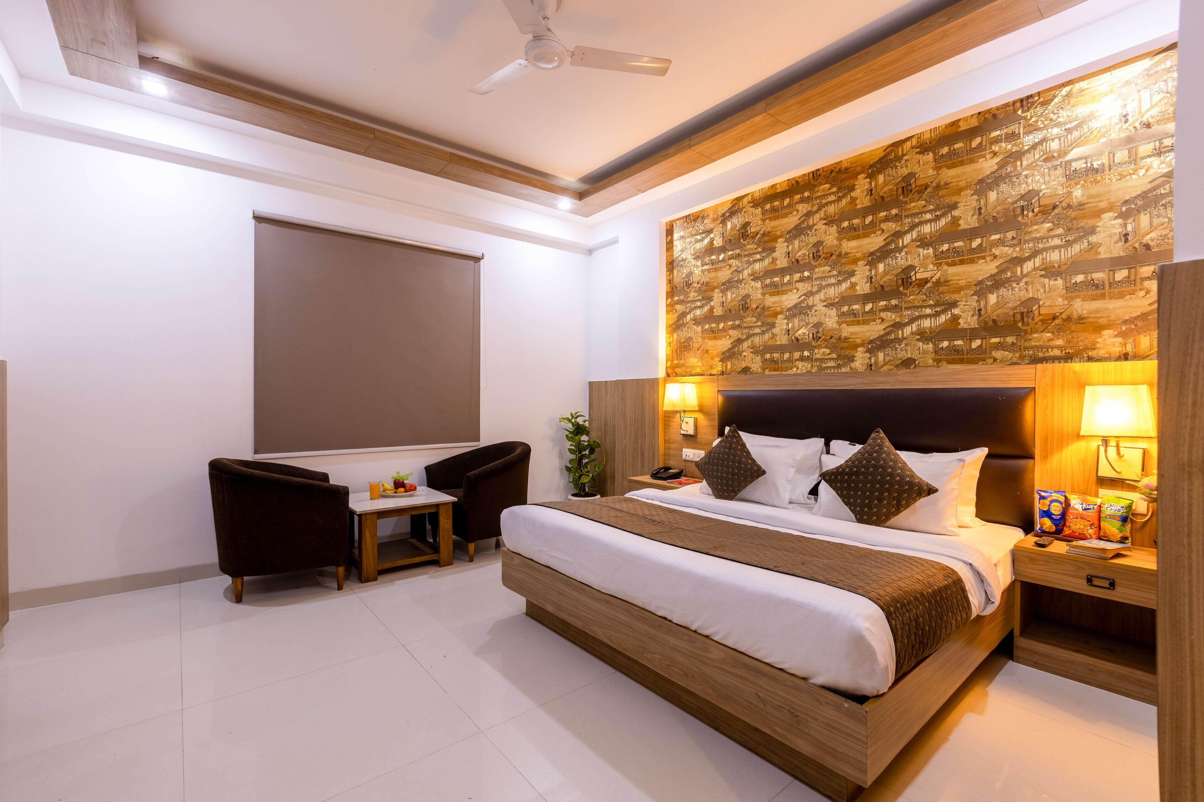 A hotel room with a large bed, a desk, a chair, and a wall-mounted TV.