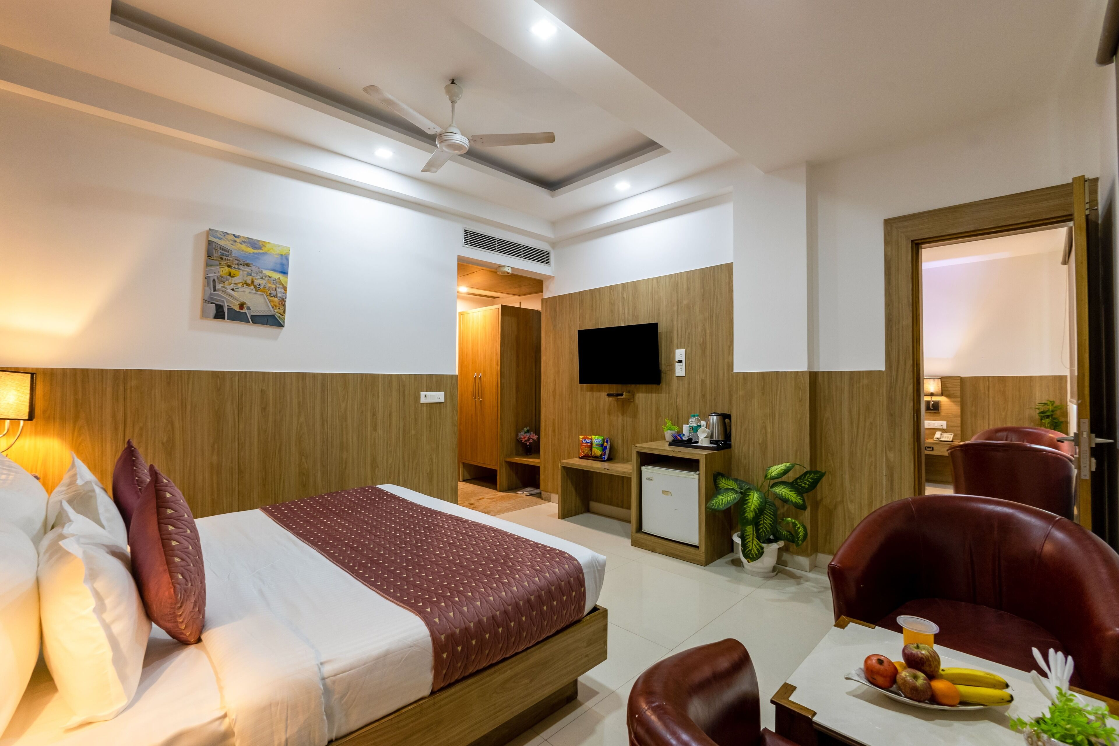 A hotel room with a bed, a desk, a chair, a television, and a small refrigerator.
