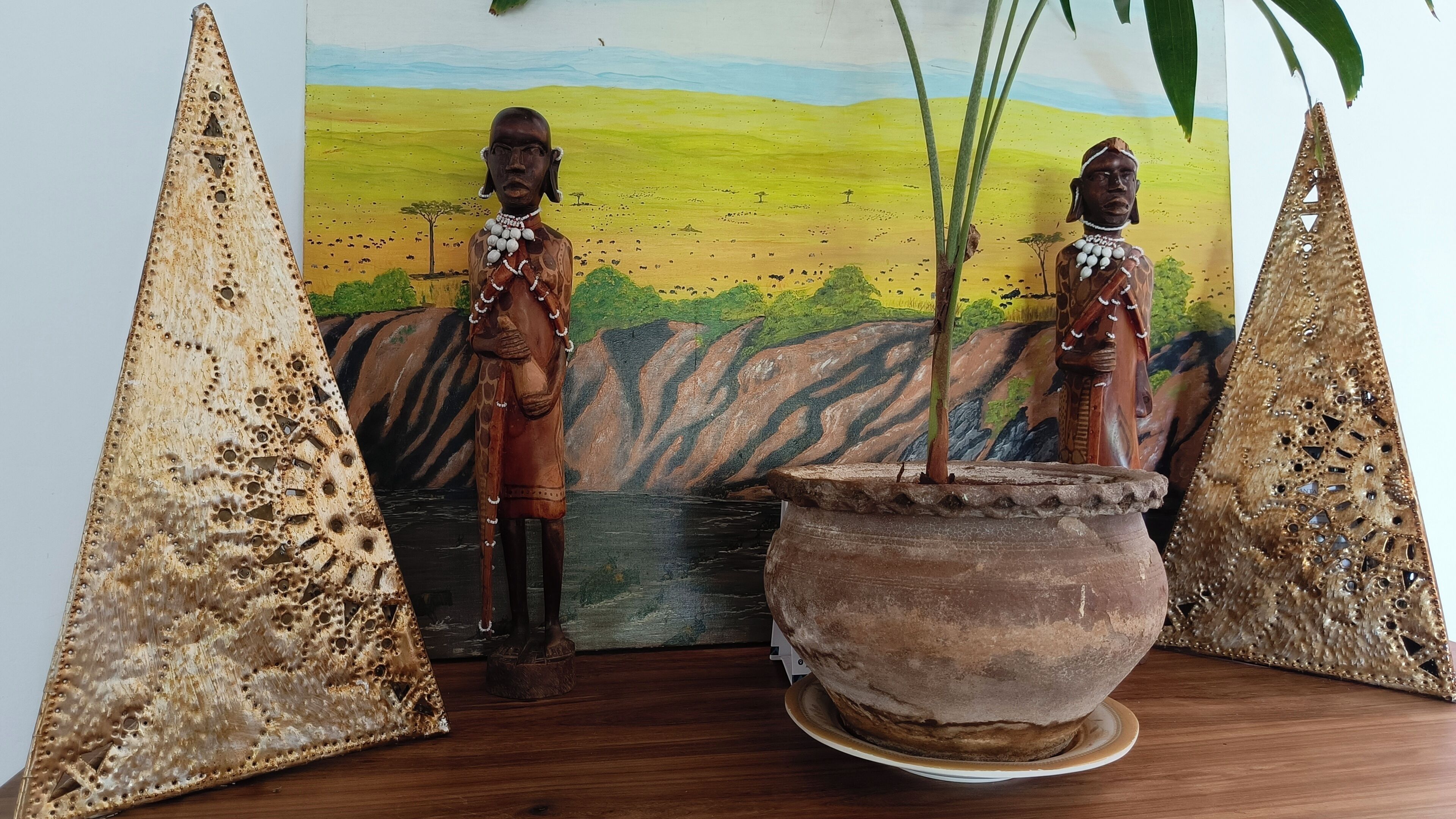 Two wooden sculptures with a painted landscape in the background.