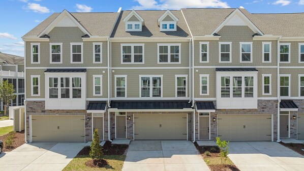 A multi-story residential building with a symmetrical facade, multiple garage doors, and a central entrance with a small porch.