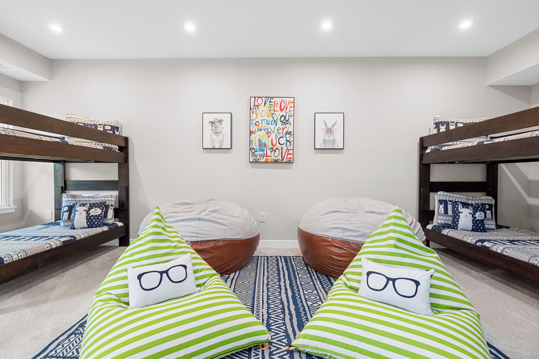 A dormitory room with bunk beds, bean bags, and a colorful wall art piece.