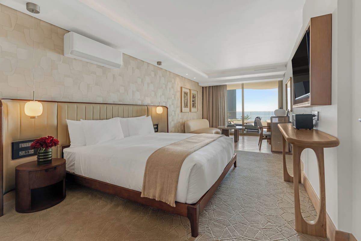Une chambre d’hôtel avec un grand lit, des tables de chevet, une télévision et une vue sur l’extérieur.