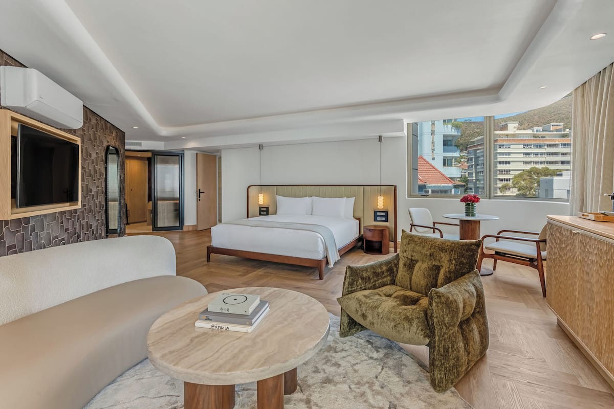 Une chambre d’hôtel moderne équipée d’un lit, d’un canapé, d’un coin repas et offrant une vue sur la ville.