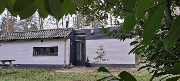 Un petit bâtiment d’un seul étage, avec un toit recouvert de tuiles, une porte noire et une fenêtre.