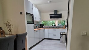 Una cocina moderna con armarios blancos, un tragaluz y vistas al exterior.
