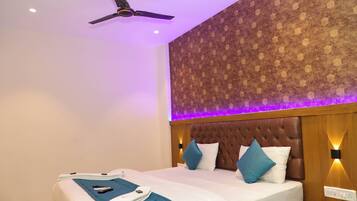 A hotel room with a bed, a ceiling fan, a patterned wall, and a wall-mounted light fixture.
