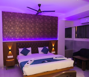 Ein modernes Hotelzimmer mit einem großen Bett, einem Deckenventilator und einem gemusterten Kopfteil.