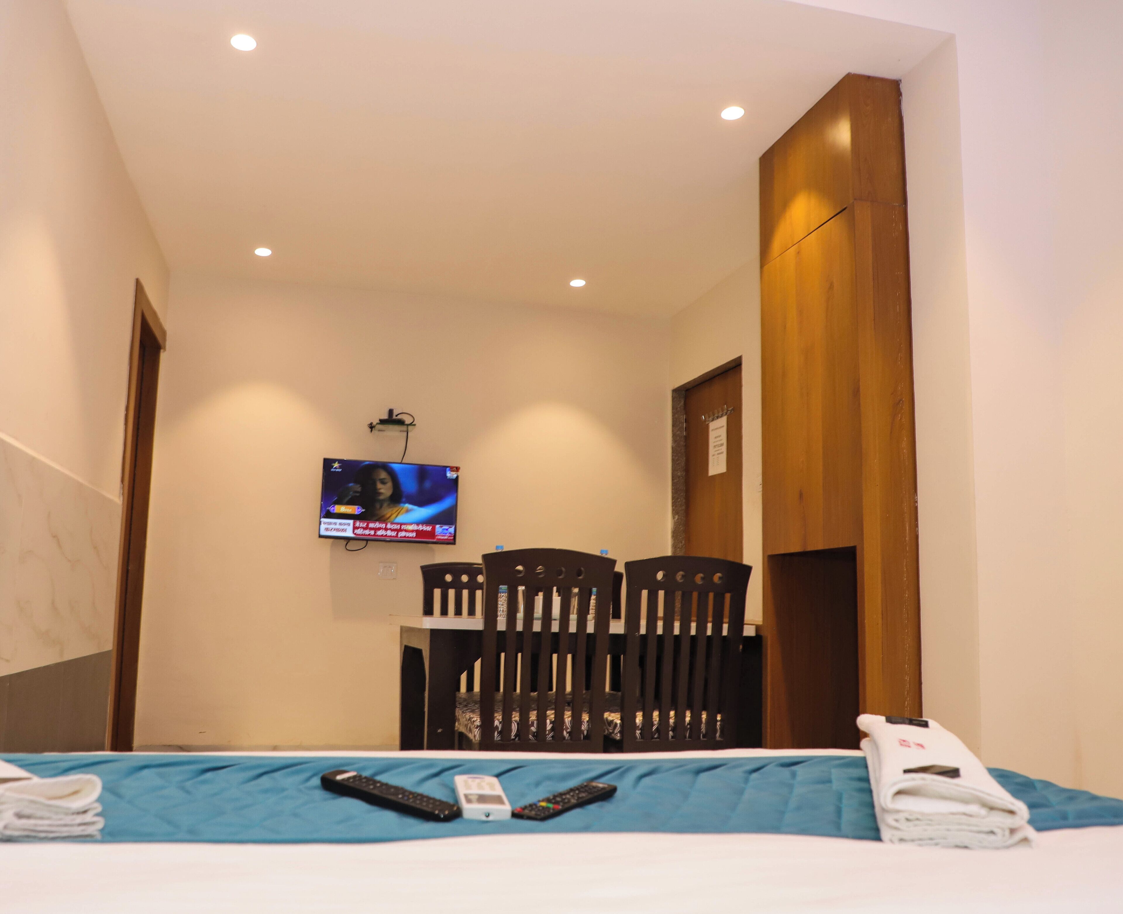 Habitación de hotel con una cama, televisión montada en la pared, escritorio con silla y armario de madera.