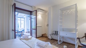 Une chambre d’hôtel avec un lit, une armoire, un radiateur et une vue sur une terrasse extérieure.