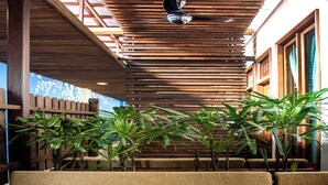 Un espace détente avec des lattes de bois, des plantes vertes et des coussins rouges.