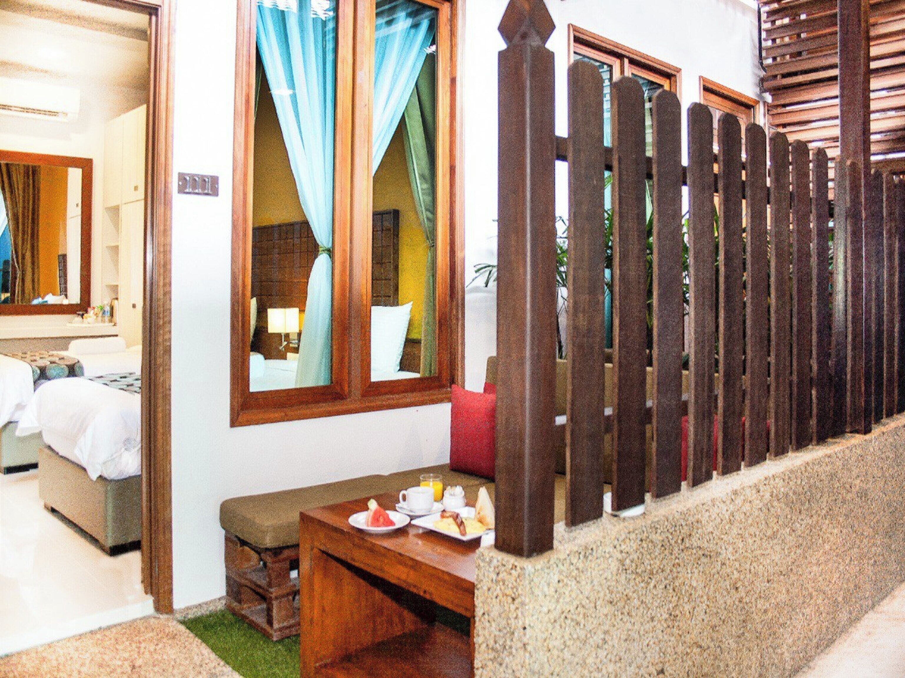 A hotel room with a bed, a small table with breakfast items, and a wooden fence outside.