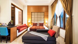 Une chambre d’hôtel avec un lit, un canapé, un bureau et une grande fenêtre avec des rideaux.