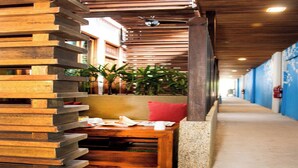 Un couloir avec un banc en bois, un coussin rouge et une plante.