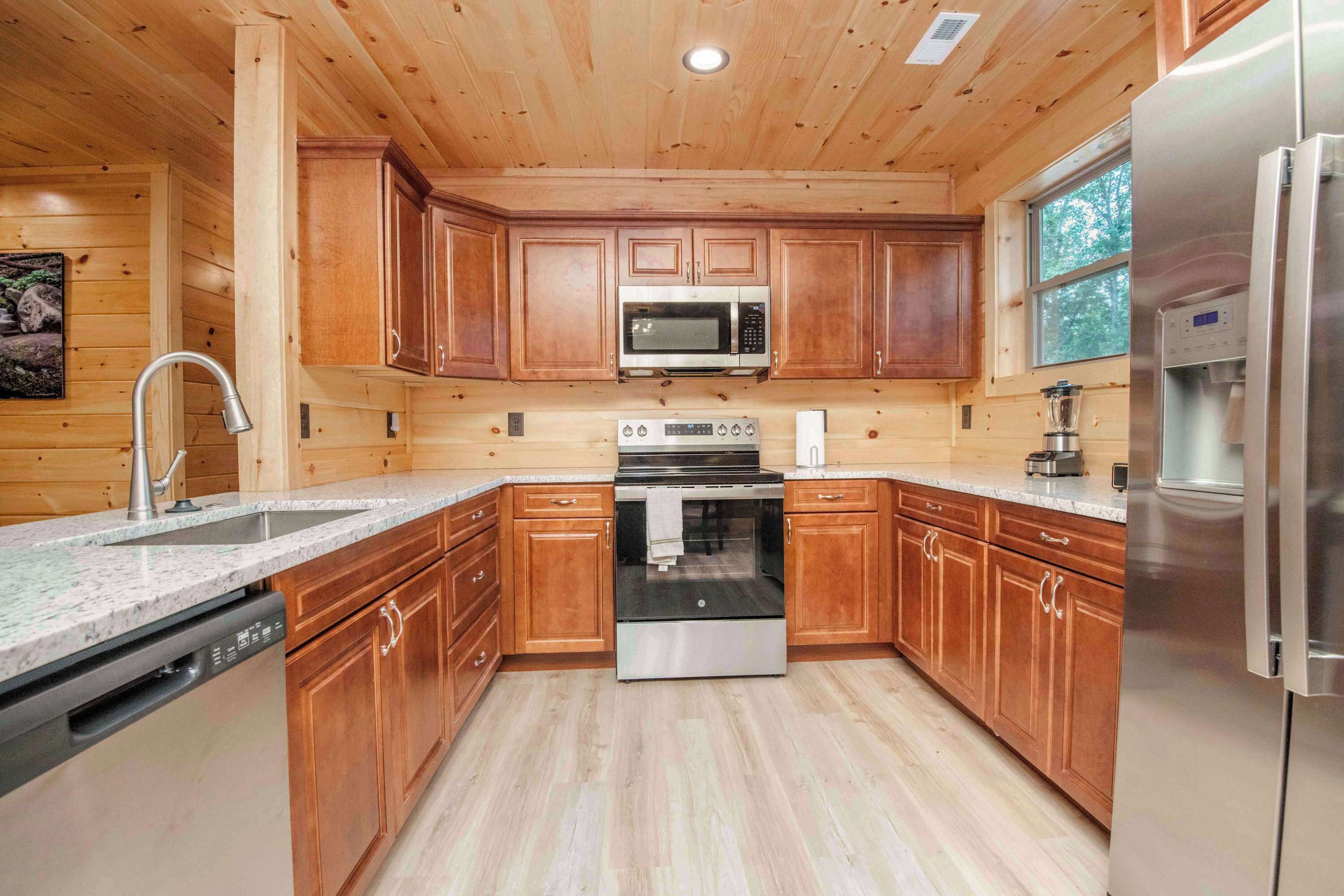 A kitchen with wooden cabinets, a stainless steel microwave, an oven, and a refrigerator.