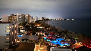 Un resort con piscina, playa y el perfil urbano al fondo.